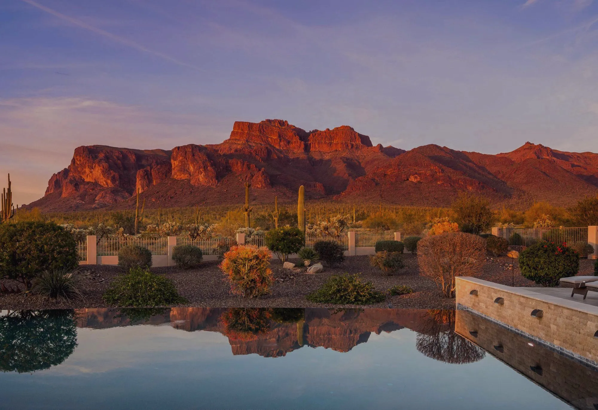 Infinity pool reflecting red-rock desert mountains at sunset
