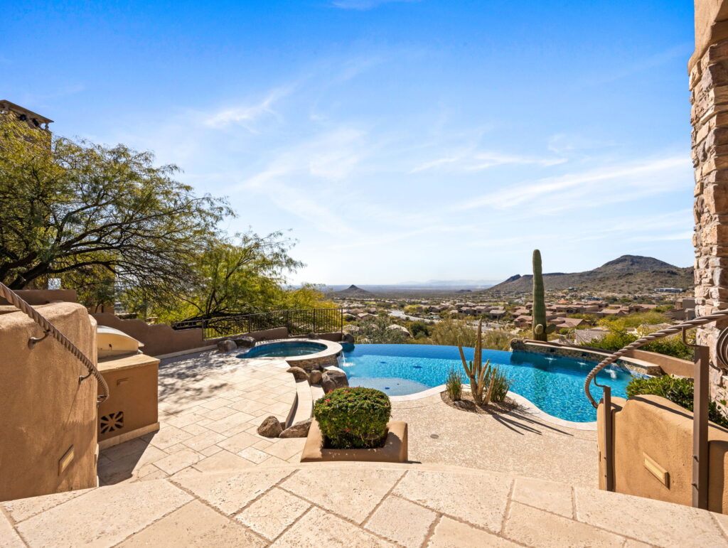 Sonoran Skyline resort-style backyard with negative-edge pool, spa, summer kitchen, and putting green